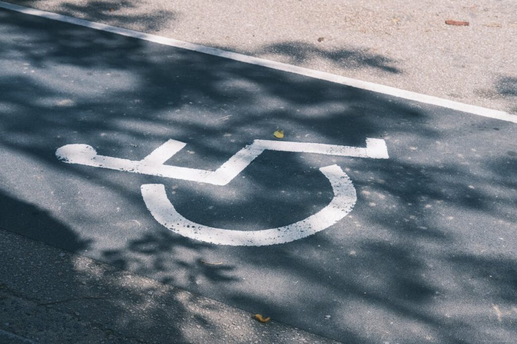 Close-up of an accessible parking symbol on a sunlit asphalt road.